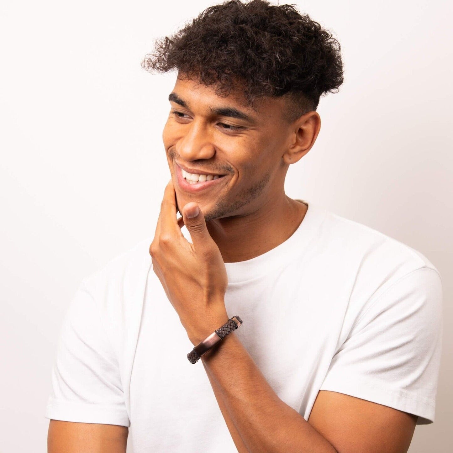 Smiling man wearing Fred Bennett brown leather bracelet with braided design and magnetic clasp