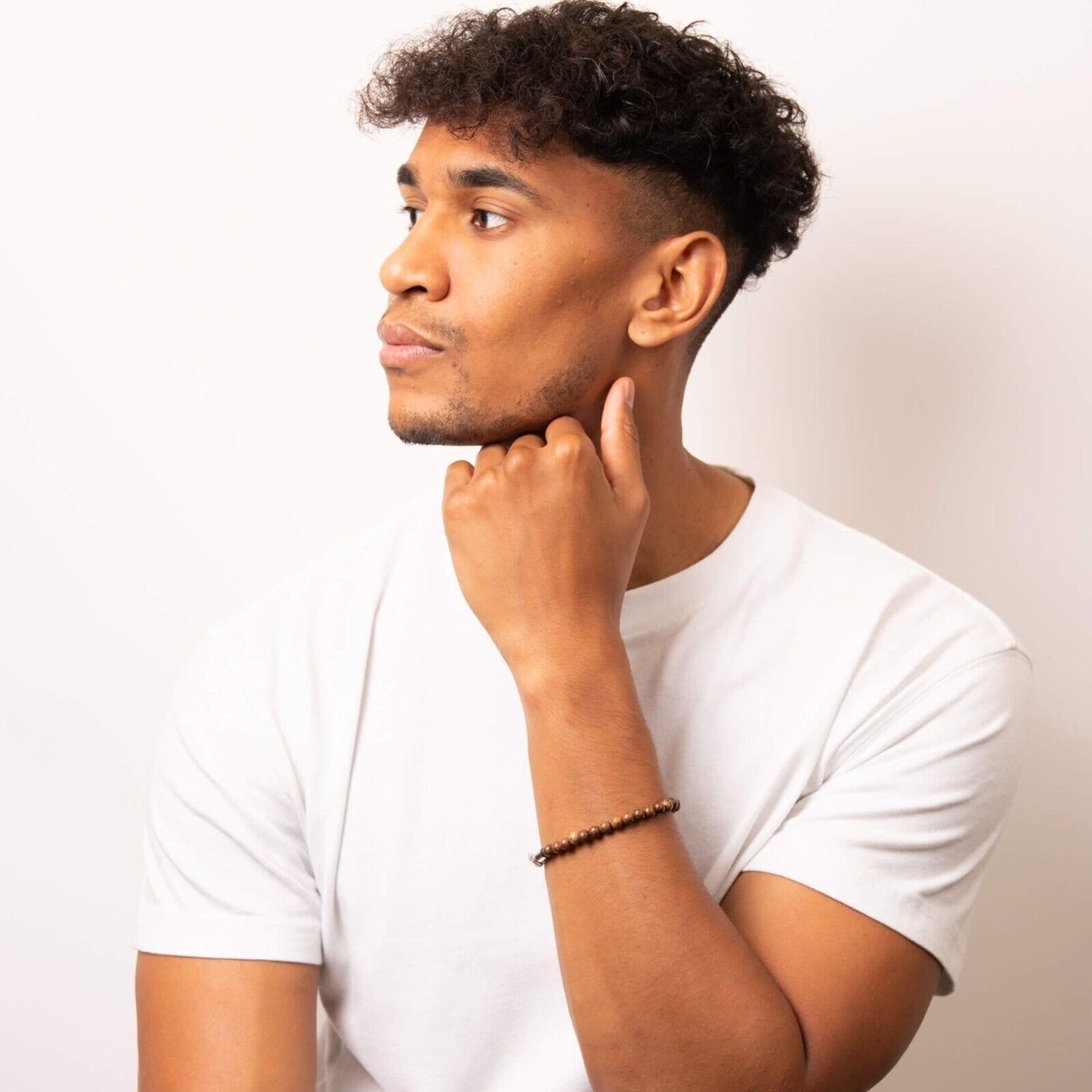 Man wearing a men's brown wooden bead bracelet by Fred Bennett on wrist with white t-shirt