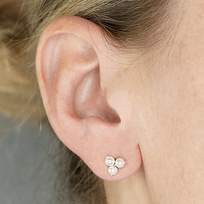 Sterling silver pearl stud earrings worn on ear featuring a cluster of three pearls