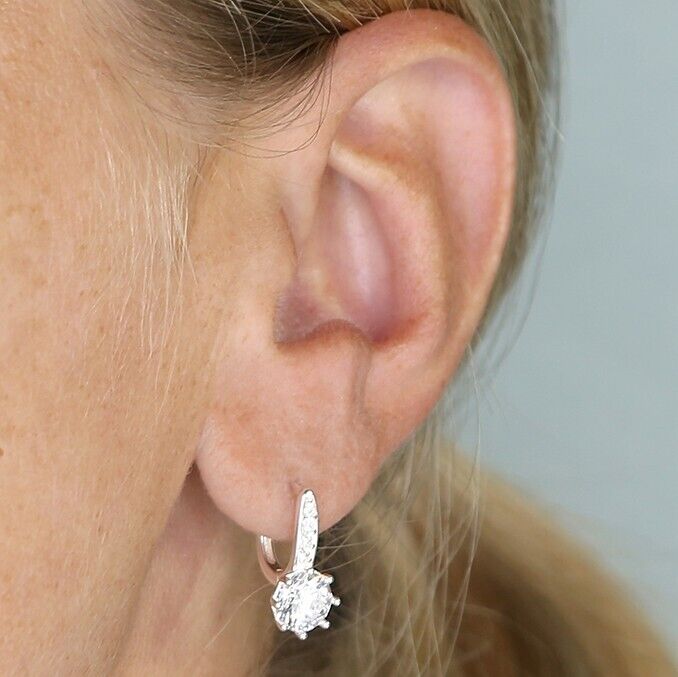 Sterling silver simulated diamond hoop earrings displayed on a model's ear