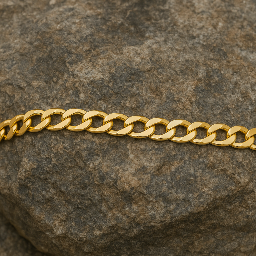 18ct Gold Mens Flat Curb Bracelet elegantly laid on a textured stone surface