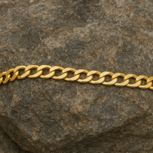 18ct Gold Mens Flat Curb Bracelet elegantly laid on a textured stone surface