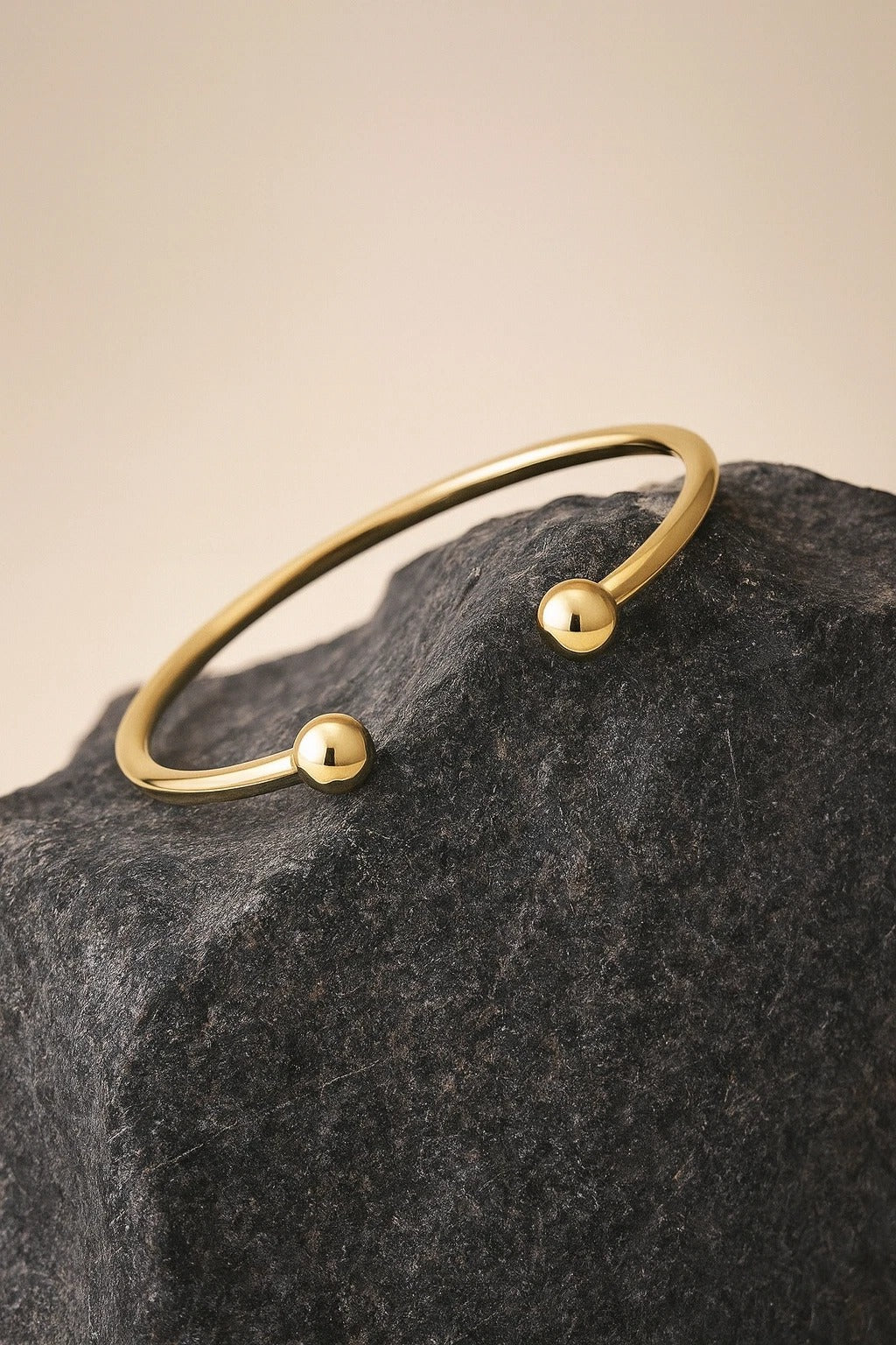 Stylish 18ct Gold Mens Torque Bangle resting on a textured stone surface, showcasing its modern design