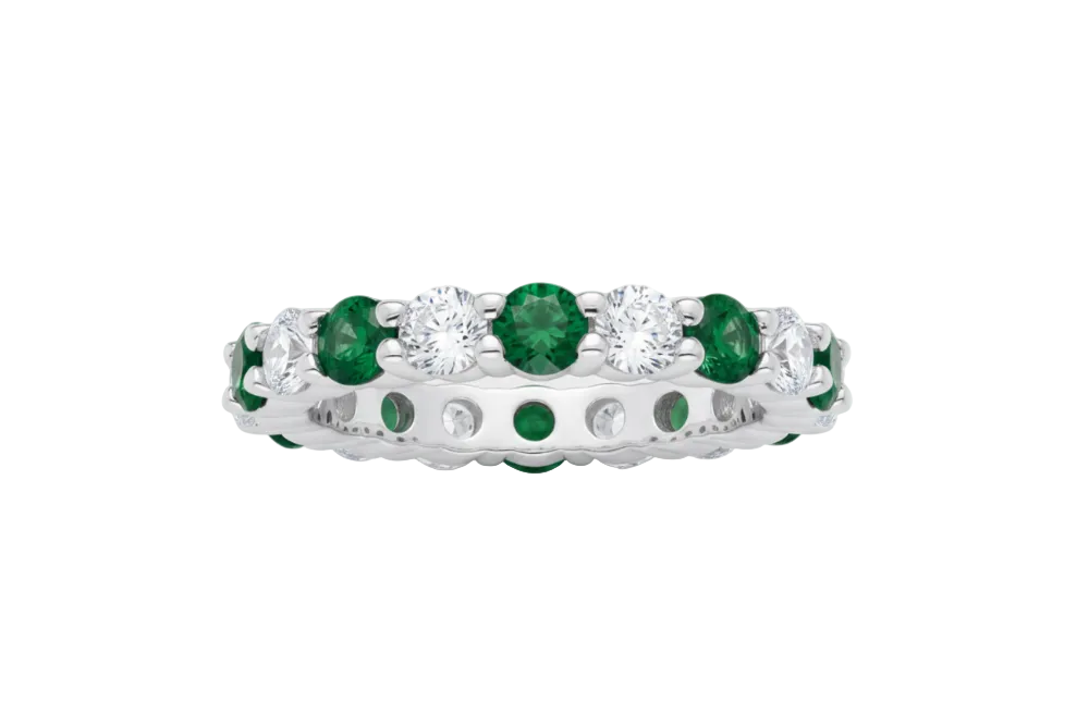 Silver ring with green gemstones on a white background