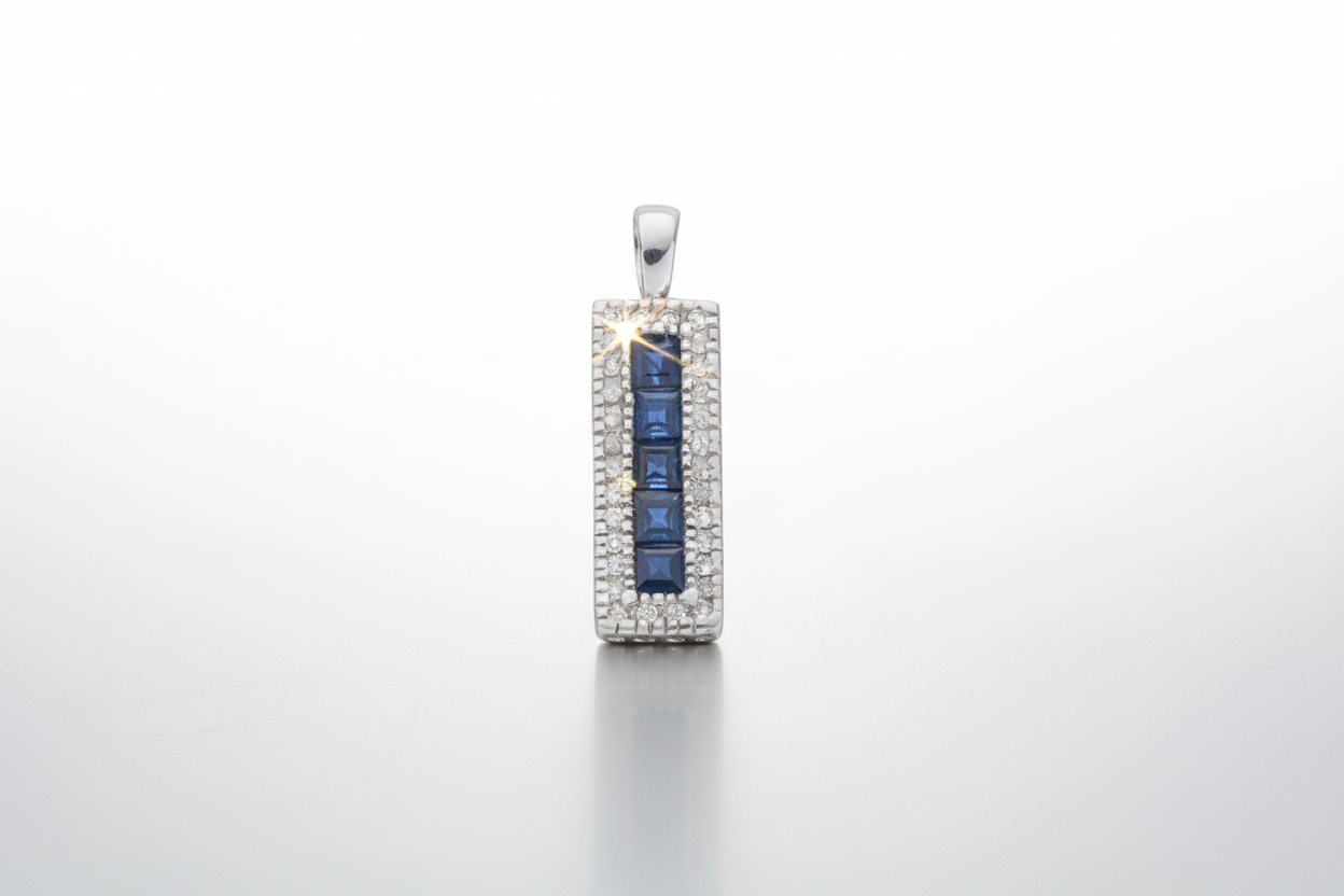 A 9ct white gold rectangular pendant with a central sapphire and surrounded by diamonds