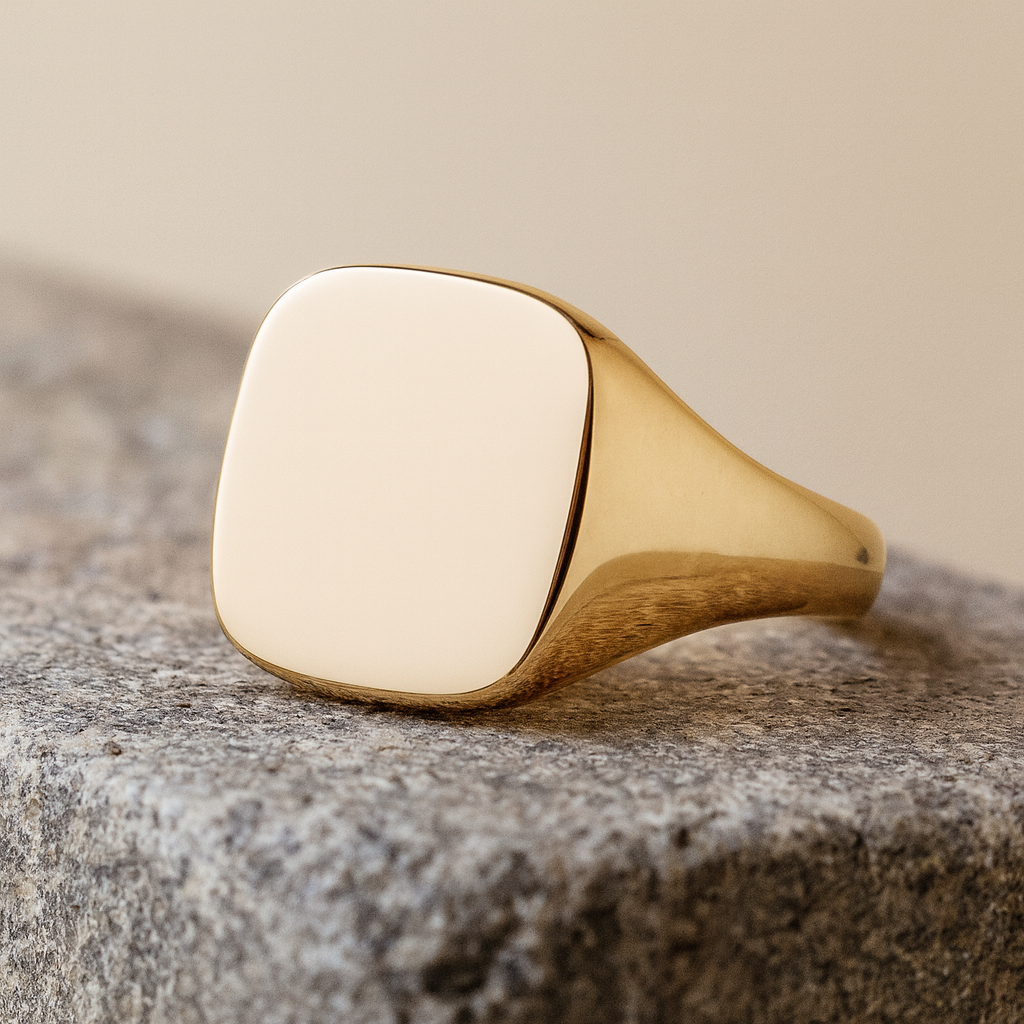 Mens 24ct Gold Cushion Signet Ring On Solid Sterling Silver displayed on a stone surface