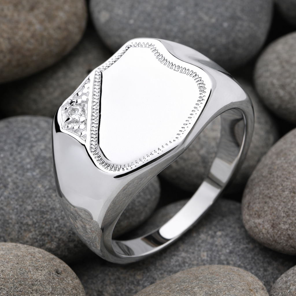 J R Jewellery Mens Shield Signet Ring in polished silver on smooth pebbles