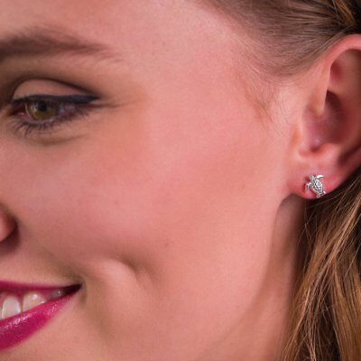 Close-up of a woman's ear wearing sterling silver turtle stud earrings by J R Jewellery