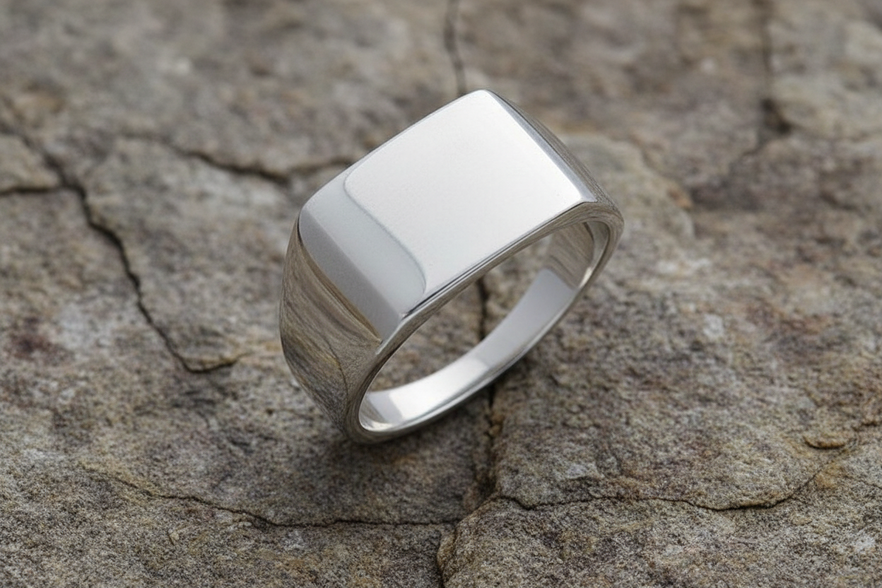 Polished silver signet ring jewellery with a sleek design on a textured stone surface