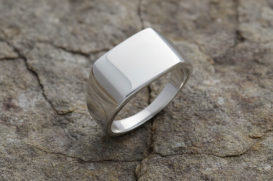 Polished silver signet ring jewellery with a sleek design on a textured stone surface