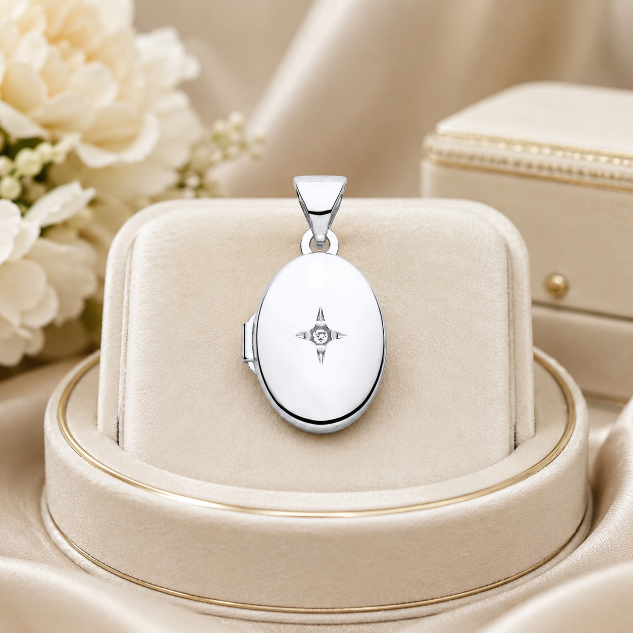 Small Oval Locket in polished silver, displayed on a beige jewellery stand with floral background