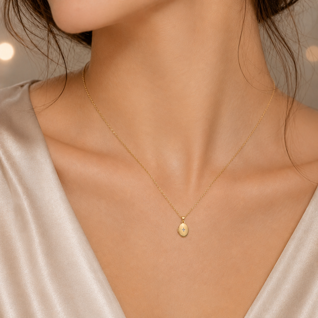 Small Gold Oval Locket on a delicate chain worn on a woman's neck with a soft satin blouse